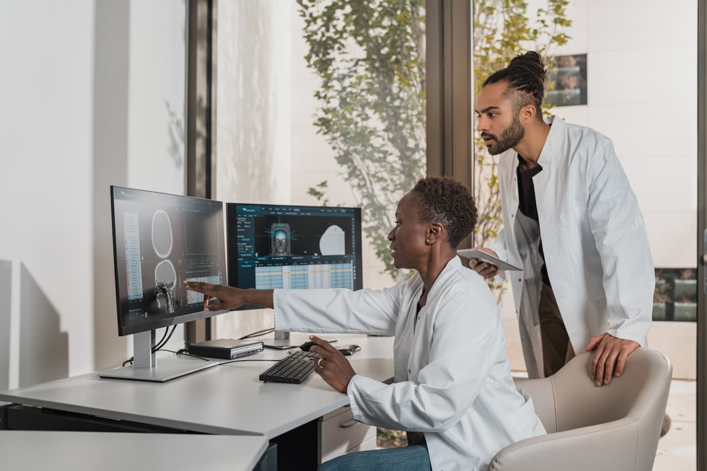 Two clinicians reviewing scans on screen