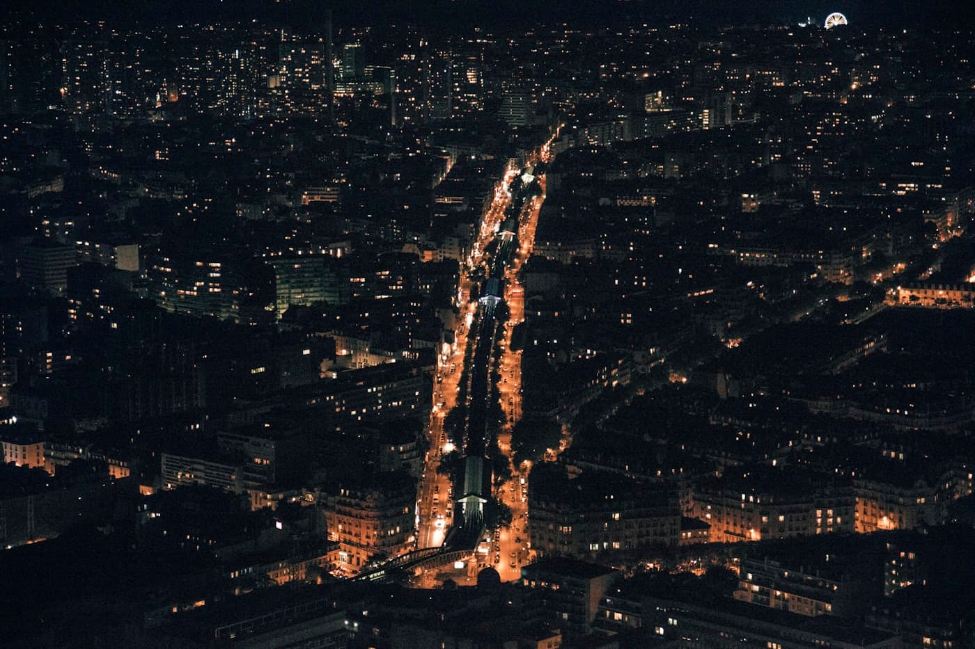 A city at night from above, lit avenues running through it